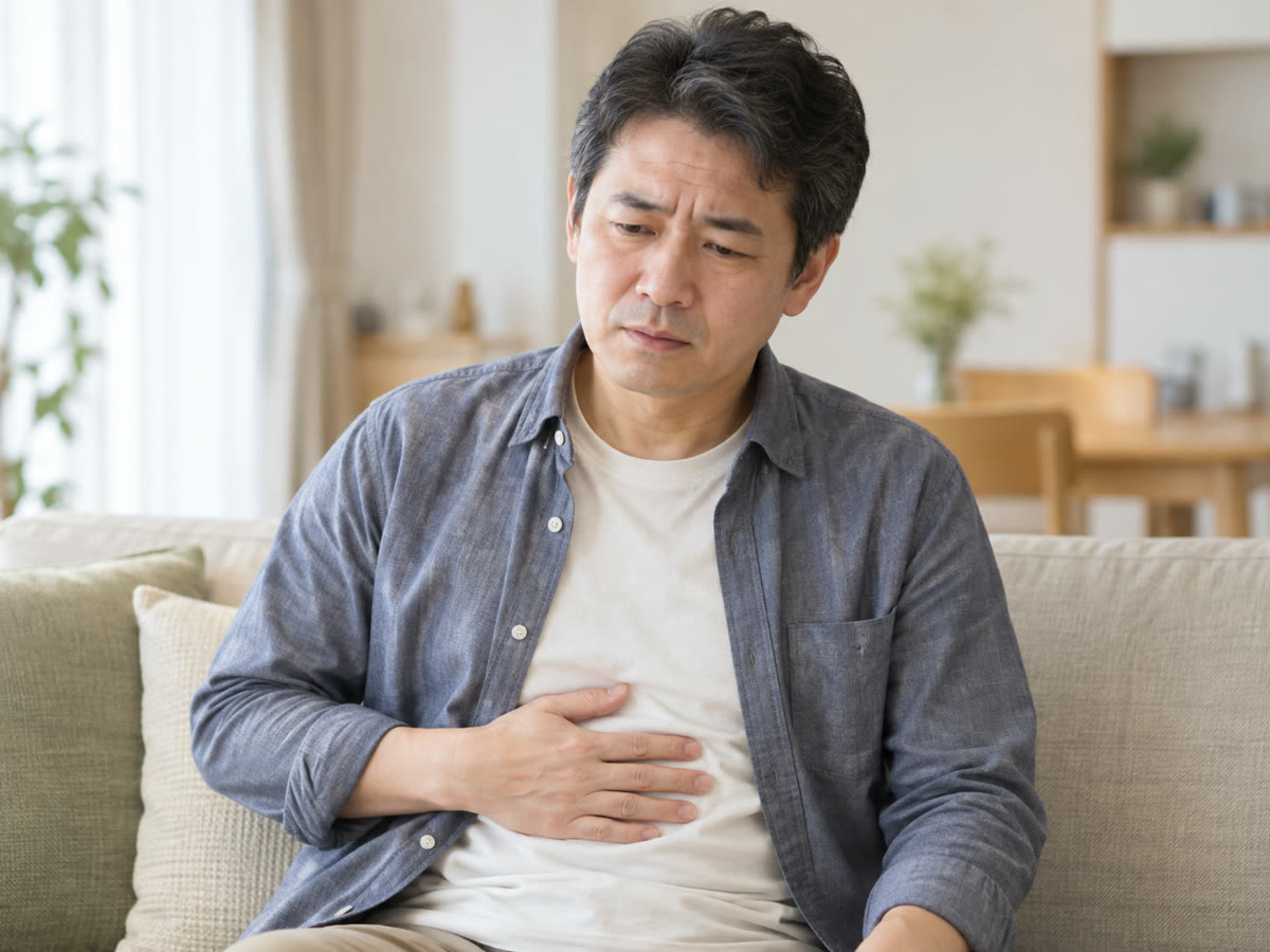 お腹に手を当てる男性